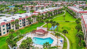 Un complejo turístico con varias edificaciones, una piscina central y abundante vegetación circundante.
