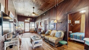 A rustic interior with wooden floors, a sofa, a bed, and a dining area. - Fabulous oceanfront home with ocean view, WiFi, washer/dryer, & central AC (St. Augustine)