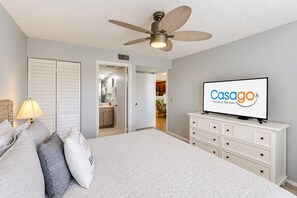 A bedroom with a bed, a ceiling fan, a television, and a dresser.