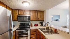 A kitchen with wooden cabinets, stainless steel appliances, a microwave, a toaster, and a sink.