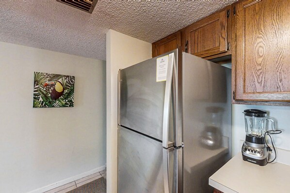 A kitchen with a stainless steel refrigerator, wooden cabinets, and a blender on the counter. - 3rd-floor condo w/fountain views, private balcony & W/D, on-site pool & hot tubs (St. Augustine)