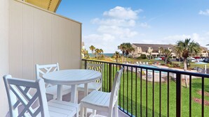 A balcony with white furniture, a view of a beach, and a building in the background. - A1A South St Augustine | 2 bedroom Oceanview Condo | Sleeps 8 (St. Augustine)