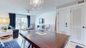 A spacious living area with a wooden dining table, a ceiling fan, and a modern chandelier. - A1A South St Augustine | 2 bedroom Oceanview Condo | Sleeps 8 (St. Augustine)