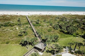A coastal property with a long wooden bridge leading to a beach.