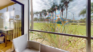 Une pièce dotée d’une grande fenêtre donnant sur un jardin avec des palmiers et une pelouse.