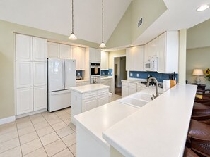 A modern kitchen with white cabinetry, a central island, and pendant lighting.