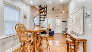 Un coin repas avec une table et des chaises en bois, un escalier en colimaçon et une carte accrochée au mur.