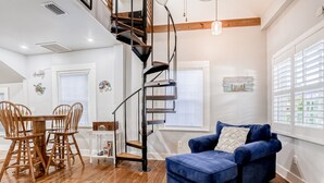 Un salon moderne avec un canapé bleu, une table à manger en bois et un escalier en colimaçon.