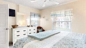 A bedroom with a bed, dresser, and a window with blinds.