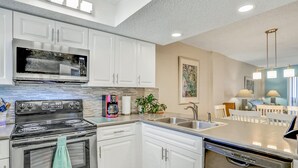 A modern kitchen with white cabinets, stainless steel appliances, and a central island with a sink.