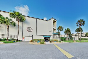 A building with a large circular emblem on the facade, a gated entrance, and palm trees in the surrounding area.