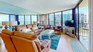 Een ruime woonkamer met een leren bank, een salontafel en een televisie. Grote ramen bieden uitzicht op de skyline.