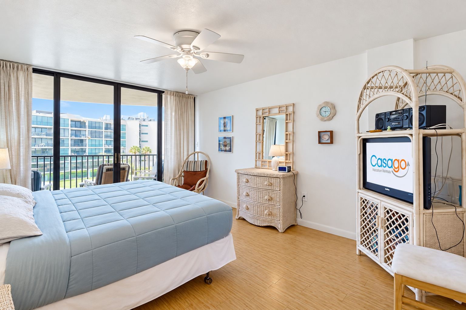 A hotel room with a large bed, a ceiling fan, a television, and a view of the city.