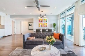 A modern living room with a grey sofa, a coffee table, and a ceiling fan. - Salute de Sailing Tower - Palace Garden District 1 (Ho Chi Minh City)