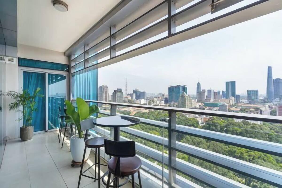 A balcony with a city view, potted plants, and a table.