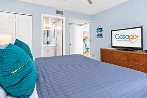 A hotel room with a bed, a television, a dresser, and a sign for Casago Vacation Rentals.
