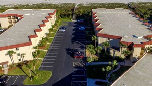 Un hotel con estacionamiento, varias construcciones y una playa al fondo.