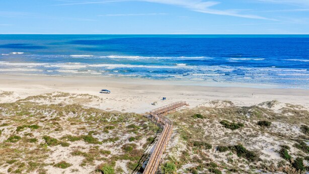 A beach with a wooden boardwalk leading to the water, sandy dunes, and a clear blue sky. - Ground-floor condo next to the tennis courts with 2 pools, sauna, beach access (St. Augustine)