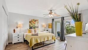 A bedroom with a bed, bedside tables, a ceiling fan, and a window with a view. - Ground-floor condo next to the tennis courts with 2 pools, sauna, beach access (St. Augustine)