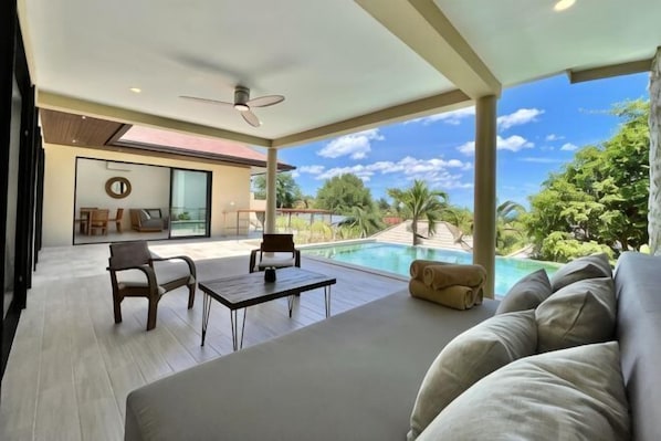 A modern outdoor living area with a pool, a sofa, and a table.