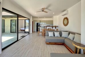 A modern living room with a sofa, a dining table, and a kitchen in the background. - Villa Marie, 2 Bedrooms, Lamai Koh Samui (Koh Samui)