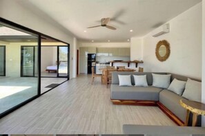 A modern living room with a sofa, a dining table, and a kitchen in the background. - Villa Marie, 2 Bedrooms, Lamai Koh Samui (Koh Samui)