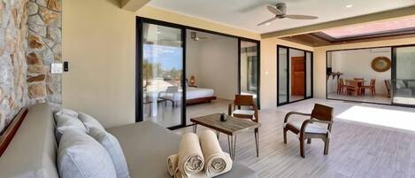 A modern living area with a sofa, chairs, a table, and a balcony with a view.