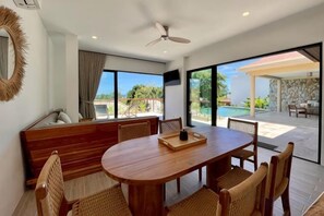 A dining area with a round table and chairs, a sofa, and a view of the outdoors. - Villa Marie, 2 Bedrooms, Lamai Koh Samui (Koh Samui)