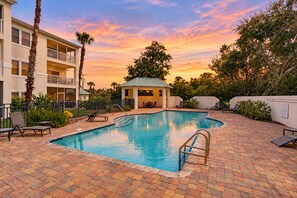 A swimming pool with lounge chairs and a small pavilion, surrounded by a brick patio and palm trees. - Dog-friendly vacation home close to the beach with pool & screened porch (St. Augustine)