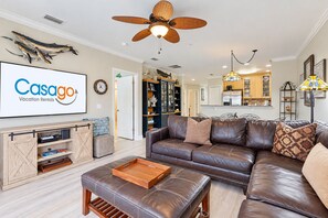 A living room with a brown leather sofa, a wooden coffee table, and a ceiling fan. - Dog-friendly vacation home close to the beach with pool & screened porch (St. Augustine)