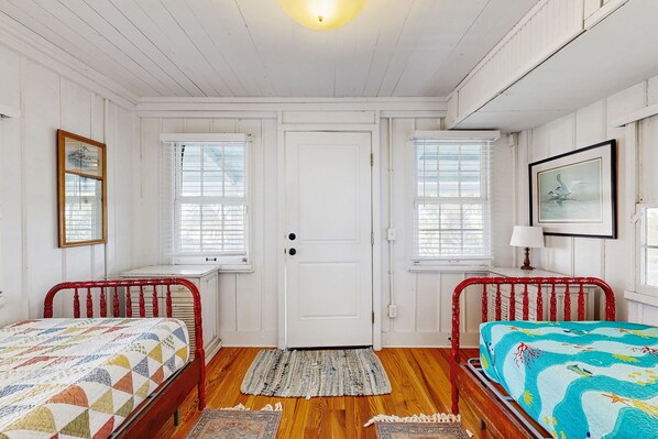 A room with two single beds, a white door, and windows with blinds. - Sunny oceanfront home with balcony, full kitchen, central AC, & washer/dryer (St. Augustine)