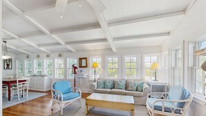 Un salon spacieux doté d’un plancher en bois, de meubles blancs et de grandes fenêtres.