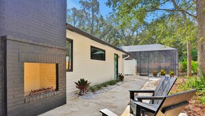 Eine moderne Außenpatio mit Feuerstelle, überdachter Sitzgelegenheit und einer Ziegelwand.
