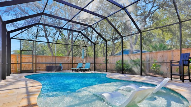 Ein überdachter Pool mit Rutsche, umgeben von einem Holzzaun und Bäumen.