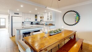 A modern kitchen with white cabinets, a wooden dining table, and a large mirror on the wall. - First floor oceanfront condo with beach access and tennis courts (St. Augustine)