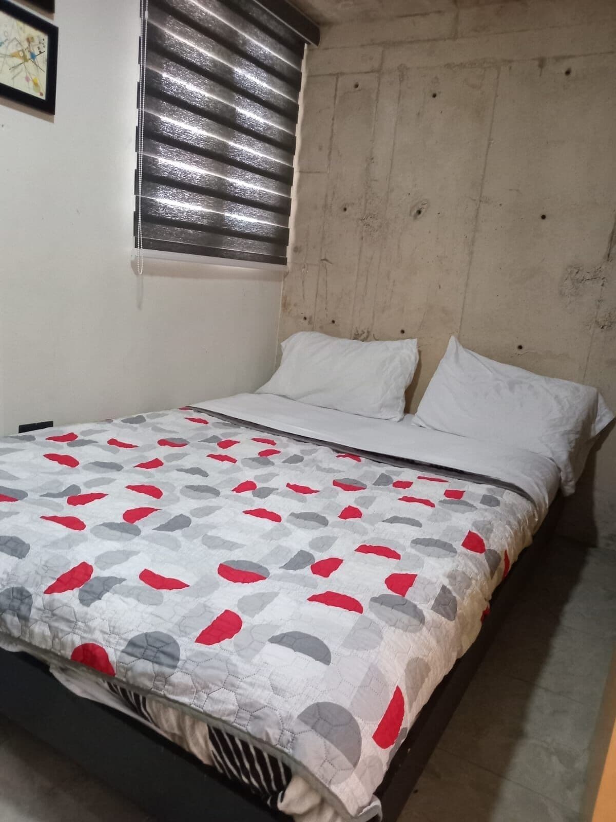 A bedroom with a bed, white pillows, and a patterned bedspread.