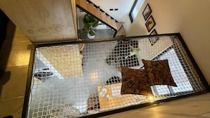 A staircase with a glass barrier, a hanging light fixture, and a plant on the landing. - Living Universidad (Puebla)