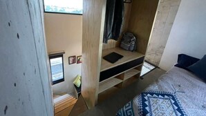 A compact room with a bed, a small wooden desk, a window, and a view of the outdoors. - Living Universidad (Puebla)