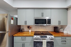 A modern kitchen with stainless steel appliances, grey cabinets, and a wooden countertop. - Spacious condo with 2 private balconies, beach access and pool (St. Augustine)
