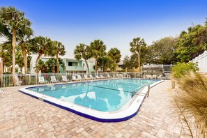 A rectangular pool with a blue edge, surrounded by lounge chairs and palm trees. - Spacious condo with 2 private balconies, beach access and pool (St. Augustine)