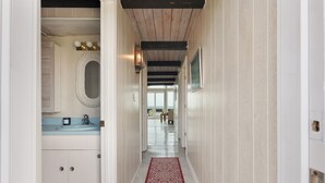 Ein Flur mit Holzboden, einem rot gemusterten Teppich und Blick in einen Raum mit Waschbecken und Schränken.