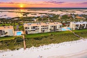 A beachfront hotel with multiple buildings, a swimming pool, and a beach area.