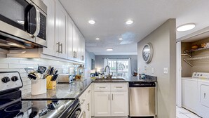 A modern kitchen with stainless steel appliances, white cabinetry, and a built-in dishwasher. - Crescent Beach Retreat, Partial Ocean View, Heated Pool, Tennis & Pickleball (St. Augustine)