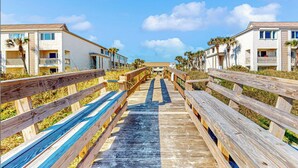 A wooden boardwalk leading to a beachfront property with multiple-story buildings, each featuring balconies and a clear view of the ocean. - Crescent Beach Retreat, Partial Ocean View, Heated Pool, Tennis & Pickleball (St. Augustine)