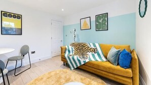 Un salon avec un canapé, une table basse, un fauteuil et une porte.