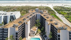 A high-rise hotel with a rooftop pool, multiple balconies, and a view of the beach.
