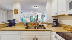 A kitchen with a granite countertop, stainless steel sink, white cabinets, a coffee maker, and a microwave. - Newly remodeled ground-floor condo w/on-site pools, 5 hot tubs, tennis, AC (St. Augustine)