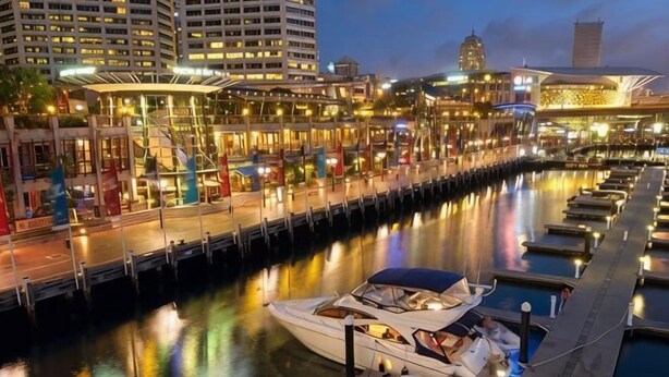 A marina with boats docked, a waterfront promenade, and buildings with illuminated facades. - A Cozy Studio CBD Next to Darling Harbour (Sydney)