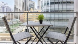 A balcony with a table and two chairs, a potted plant, and a city view. - A Cozy Studio CBD Next to Darling Harbour (Sydney)