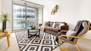 A living room with a sofa, armchair, coffee table, and a large window. - A Cozy Studio CBD Next to Darling Harbour (Sydney)